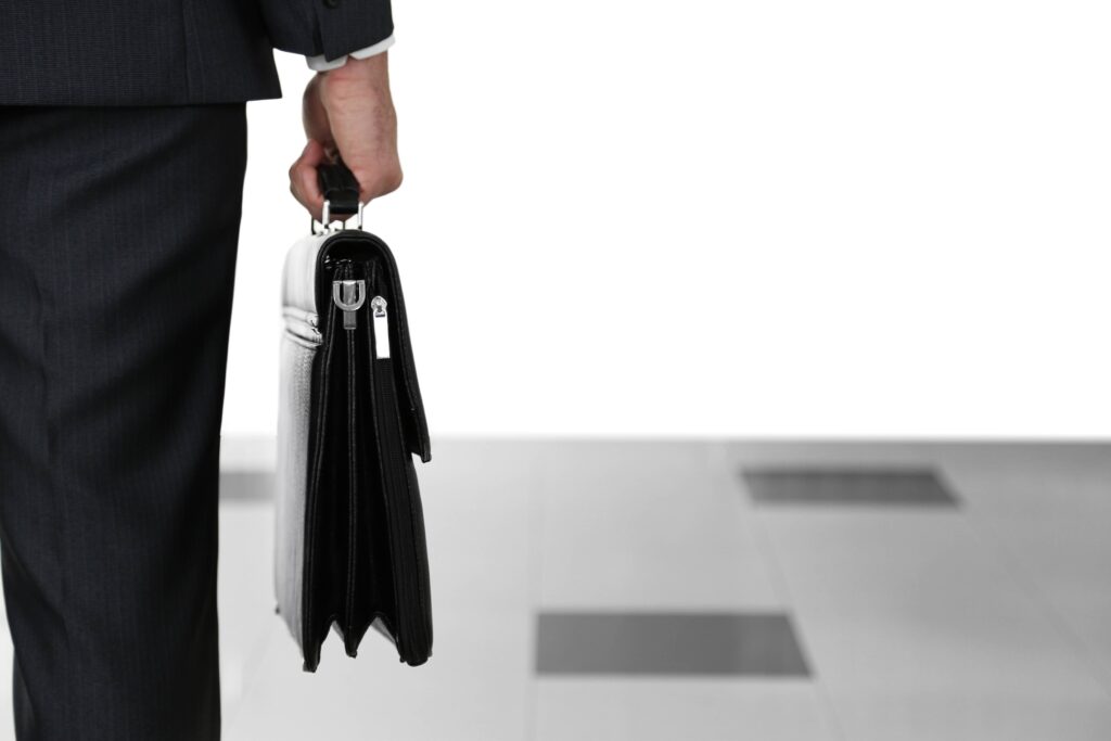 איש עסקים מאחורה עומד ומחזיק תיק עסקים